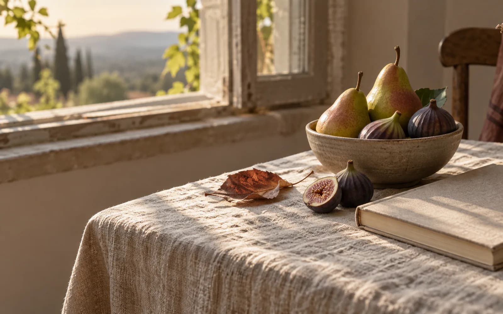 Pears and figs beside a blank journal on linen.